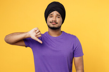 Unhappy devotee Sikh Indian man ties his traditional turban dastar wear purple t-shirt showing...