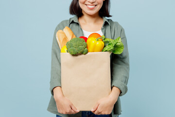 Cropped young happy woman wear casual clothes hold brown paper bag with food products after...