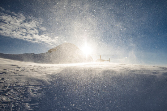 Sunlight illuminates snow and ice from helicopter rotor wash