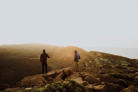 Two men stand on mountain top watching sunrise