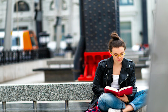 Young woman reading book, waiting at train station