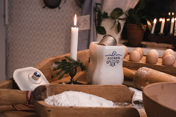 Christmas baking in a country kitchen, eggs, flour, rolling pin, standing on an old baking table. There is an Advent candlestick in the background.