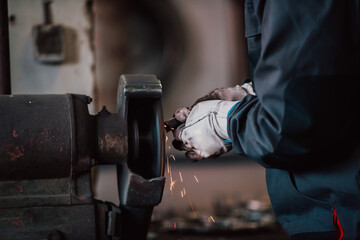 Close up of a man in gloves polishing iron materials in an industry