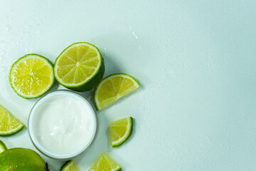 Cosmetic cream for skin care in a jar with lime. Moisturizing cream. close-up of body lotion, cream and lime on the table. Cosmetic cream with lime slices and spa bones. Selective focus.