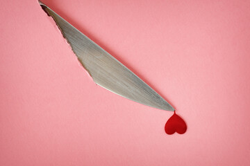Knife cutting pink sheet with heart shaped drop of blood - Concept of violence against women and...