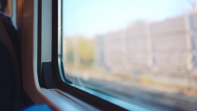 View from inside of driving fast speed train, blurred railway and exterior view, local train with passengers driving at railway station. Looking through the window of riding train, railways