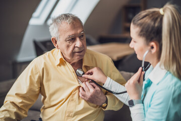 Obraz premium Home doctor is visiting senior man to check his health. Professional caregiver is assisting old man at his home.