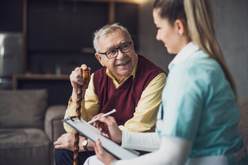 Home doctor is visiting senior man to check his health. Professional caregiver is assisting old man...