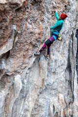 Fototapeta premium woman climbs a rock, a strong girl trains strength and endurance, extreme sport