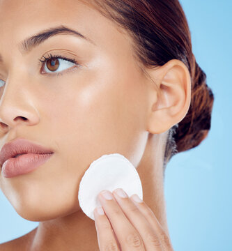 Beauty, cotton pad and face, woman removing makeup or dirt with luxury skin product in studio. Dermatology, cleaning cosmetics and facial skincare spa treatment for model isolated on blue background.