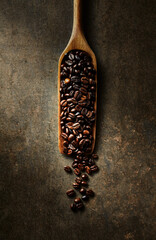 Dark coffee beans on a rustic wooden spoon. Top view