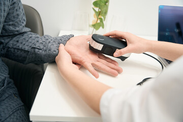 Picture of doctor hands with oligoscan is doing analysis in health center - obrazy, fototapety, plakaty