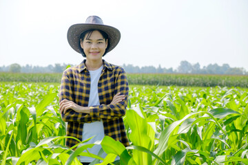 Asian female farmer in striped shirt posing cross arm at corn field