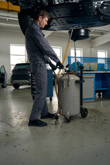 Man preparing car before repair, removing engine oil