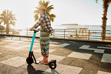 Electric scooter, retirement and woman riding on sidewalk at tropical island beach resort for happy...
