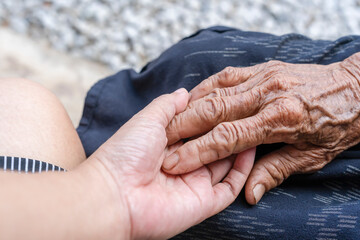 Close-up of old and young holding hands. Middle-aged mommy's wrinkled hands holding young...