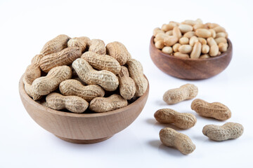Bowl full of shelled and roasted peeled peanuts on white background, closeup

