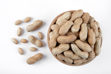 Bowl full of shelled and roasted peeled peanuts on white background, closeup