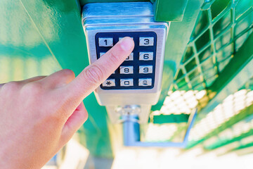 Hand enters a numeric code to open the gate lock