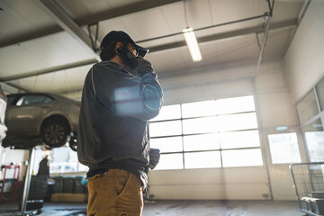 Low angle shot of a mechanic talking on the phone in a repair shop. High quality photo