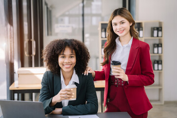 female colleague of half Asian descent holds a cup of coffee and smiles happily.