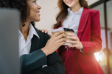 female colleague of half Asian descent holds a cup of coffee and smiles happily.