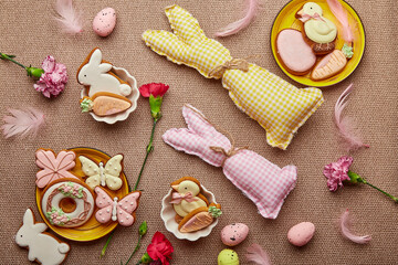 Traditional glazing Easter cookies, handmade bunny toys, pink flowers. Spring Easter aesthetic background flat lay