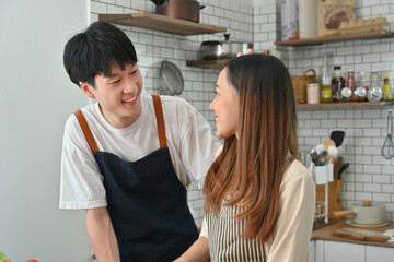 Cheerful asian man and wife having fun together in kitchen, enjoying spending free weekend time together at home