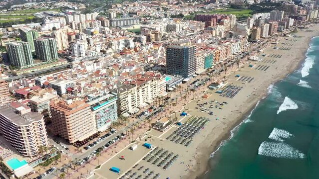 Aerial drone footage of the beautiful beach front of the coastal town of Fuengirola in Malaga Spain Costa Del Sol, showing the sandy beach, hotels and apartments on a sunny day in the summer time