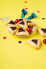 Hamantaschen Cookies, Carnival Mask, Noisemaker on Yellow Background. Purim Celebration, Jewish...