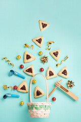 Hamantaschen Cookies, Carnival Mask, Noisemaker on Mint Green Background. Purim Celebration, Jewish Carnival Holiday Concept.