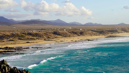 Klify oceanu atlantyckiego w Fuertaventura morze woda i plaża, surferzy i góry - obrazy, fototapety, plakaty