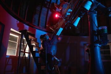 Astronomer with a big astronomical telescope in observatory doing science research of space and...