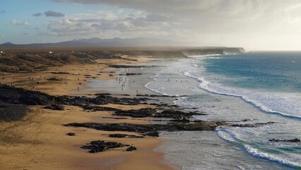 Klify oceanu atlantyckiego w Fuertaventura morze woda i plaża, surferzy i góry - obrazy, fototapety, plakaty