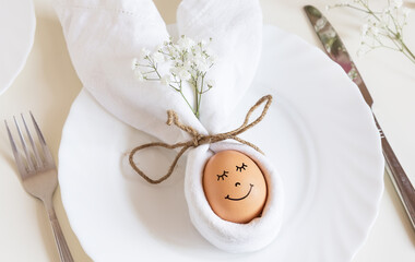 Easter egg with a cute face in a plate with bunny ears, as happy Easter concept.