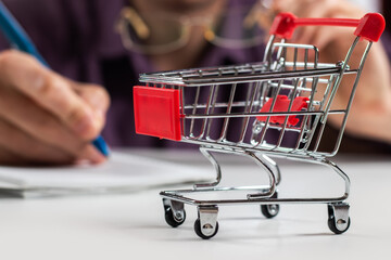 Man calculates the budget. Shopping cart a on table with calculator and paper.