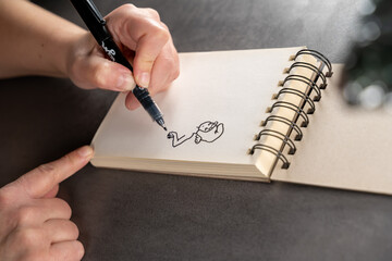 main d'un dessinatrice qui fait un croquis sur un carnet a spirale