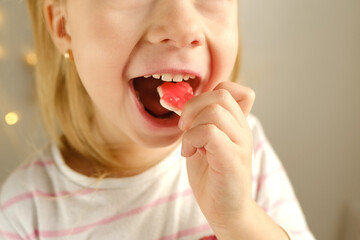 portrait of small child, blonde girl 3 years old wants to eat gelatinous sweets, gummy bear, kid...