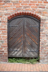 Altes, braunes Holztor an einer Backsteinmauer, Deutschland