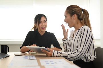 Young woman office worker telling gossips, enjoy friendly conversation with her colleague