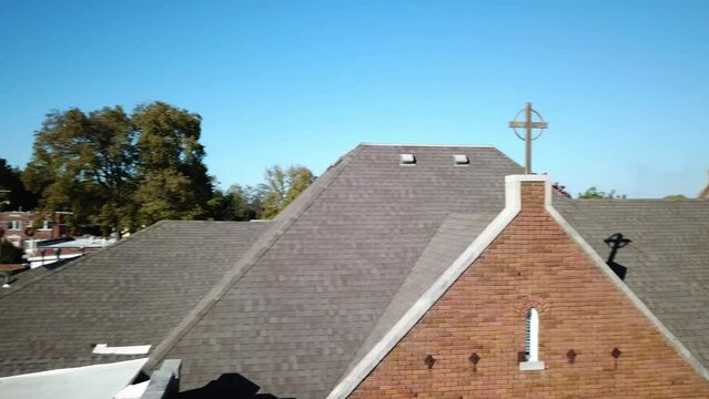 Overhead drone shot of brick building surrounded by trees under clear sky