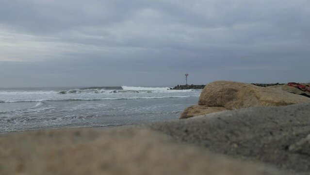 Waves crashing on jetty in Oceanside California on an overcast day.