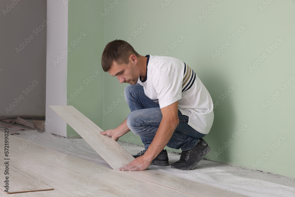 Wall mural Man installing new laminate flooring in room