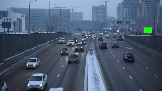 4k Urban transport view and mockup screen in city in winter spbas. Traffic is driving on highway in town with buildings, signs and lightbox for advertising in cold snowy weather. Beautiful pic of