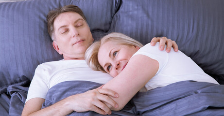 Couple in bed. Man and woman are enjoying spending time together while lying in bed. Happy middle aged couple in bedroom.