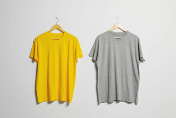 Hangers with different t-shirts on light wall. Mockup for design
