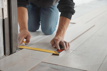 Fototapeta na wymiar Worker installing new laminate flooring in room, closeup