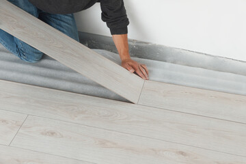 Worker installing new laminate flooring in room, closeup