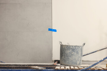 Different tools on tower tour near white wall with adhesive mix and tiles indoors