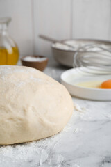 Fresh yeast dough with flour on white marble table, closeup